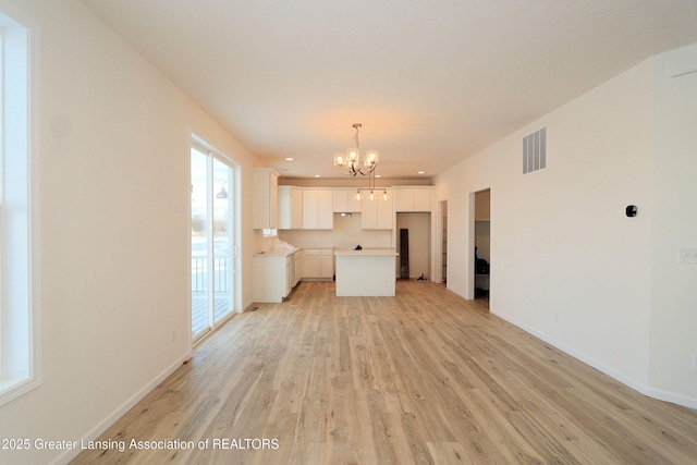 unfurnished living room with a chandelier and light hardwood / wood-style floors