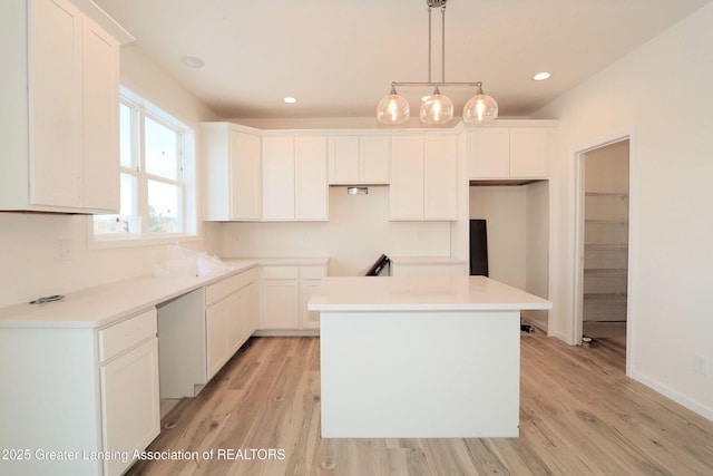 kitchen with hanging light fixtures, white cabinetry, a kitchen island, and light wood-type flooring