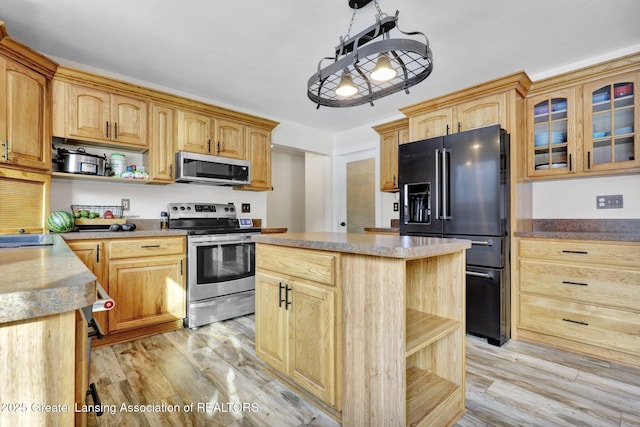 kitchen with stainless steel appliances, a center island, hanging light fixtures, and light hardwood / wood-style flooring