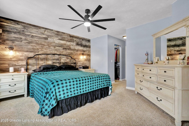 bedroom featuring light carpet, a closet, a walk in closet, and wooden walls