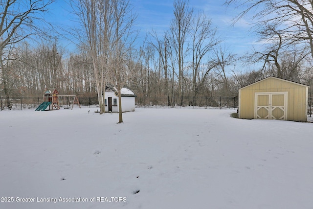 snowy yard with a playground and a storage unit