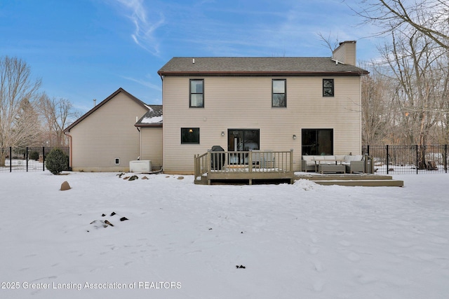 snow covered rear of property with a deck