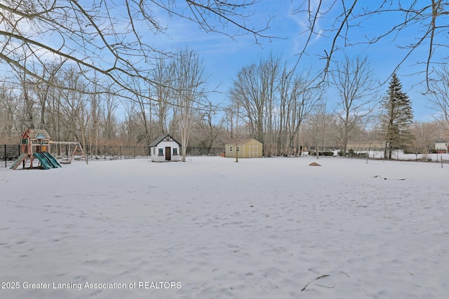 snowy yard with a playground and a storage unit