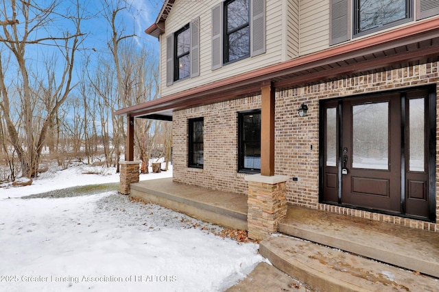 snow covered property entrance featuring a porch