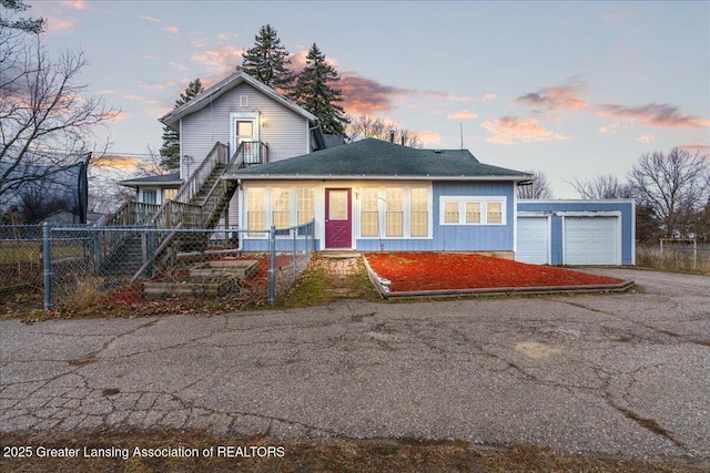 traditional-style home featuring a garage, an outdoor structure, fence, and stairs