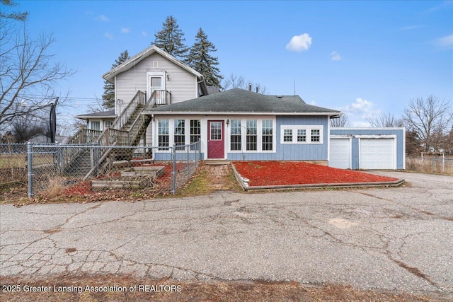 traditional-style home with an outbuilding, a shingled roof, a garage, fence private yard, and stairs