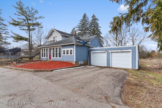 view of front of home featuring aphalt driveway, an outdoor structure, a garage, and fence