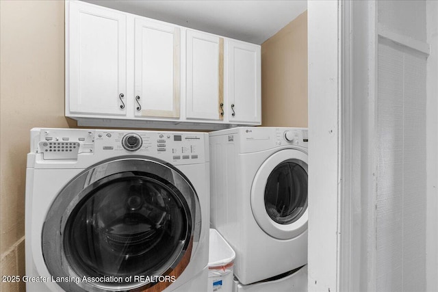 clothes washing area featuring washer and dryer and cabinet space