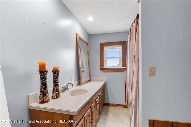 full bath featuring a textured ceiling, vanity, and baseboards