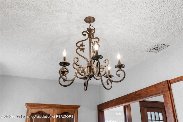 room details with a textured ceiling, visible vents, and a notable chandelier