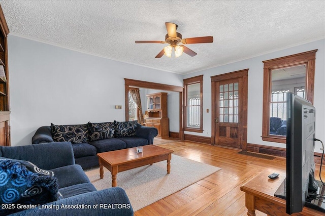 living room with ornamental molding, light wood-type flooring, ceiling fan, and a textured ceiling