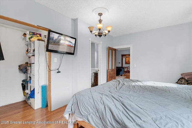 bedroom featuring a textured ceiling, an inviting chandelier, and wood finished floors