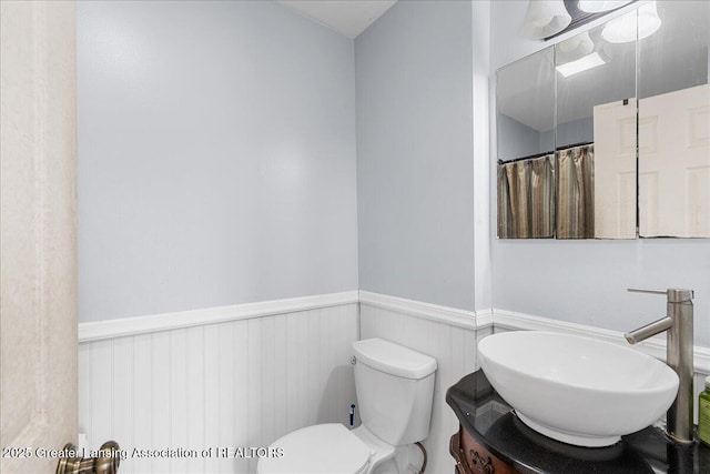 full bathroom featuring toilet, vanity, and wainscoting