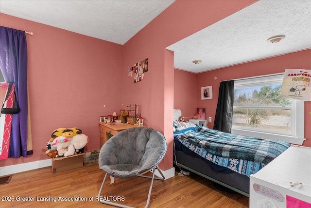 bedroom with a textured ceiling, baseboards, and wood finished floors