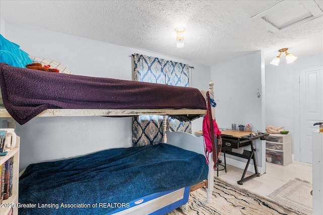 bedroom with a textured ceiling and attic access