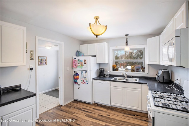 kitchen featuring pendant lighting, white cabinetry, sink, light wood-type flooring, and white appliances