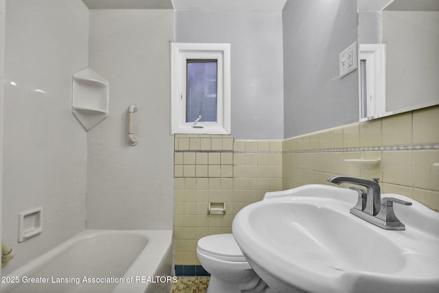 bathroom featuring toilet, a bath, sink, and tile walls