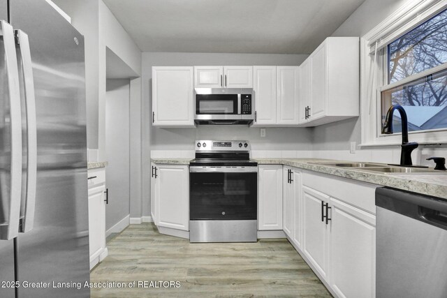 kitchen with appliances with stainless steel finishes, sink, and white cabinets