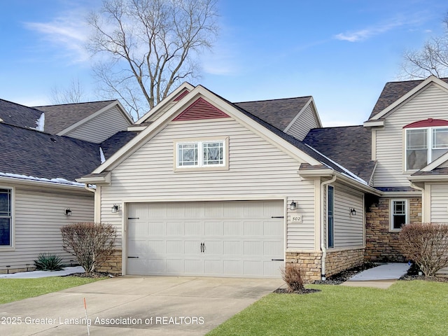 view of front of house with stone siding, roof with shingles, concrete driveway, and a front lawn