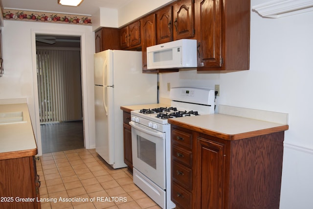 kitchen featuring sink, white appliances, and light tile patterned flooring