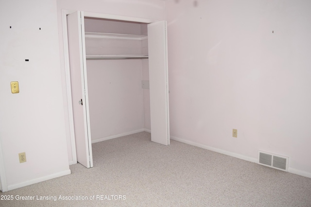 unfurnished bedroom with a closet and light colored carpet