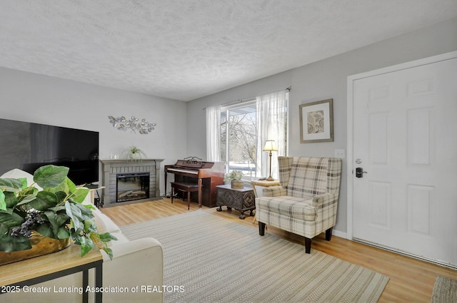 living room featuring a brick fireplace, hardwood / wood-style flooring, and a textured ceiling