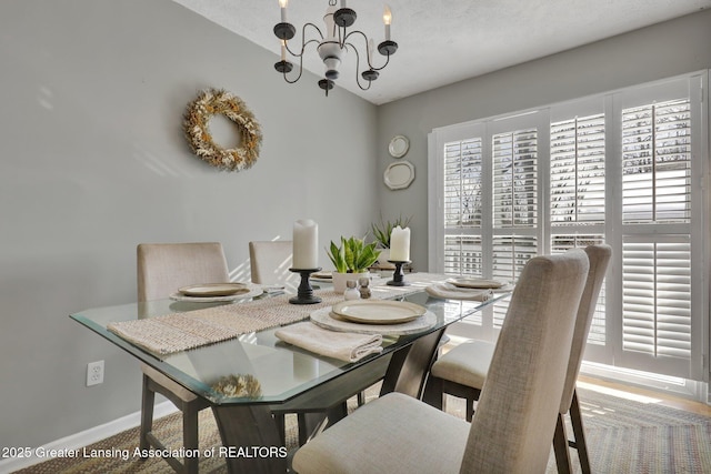 dining area featuring a textured ceiling, vaulted ceiling, and a chandelier