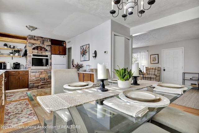 dining room featuring an inviting chandelier, a textured ceiling, and light wood-type flooring