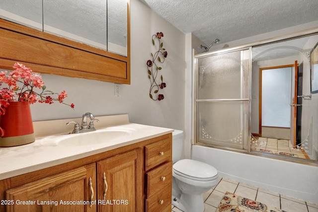 full bathroom featuring combined bath / shower with glass door, vanity, a textured ceiling, tile patterned floors, and toilet