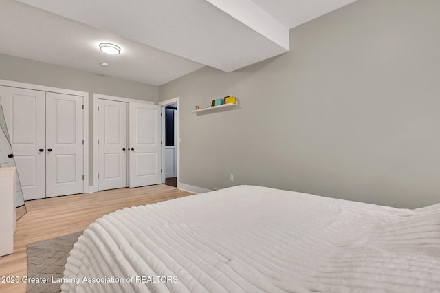 bedroom featuring multiple closets and light wood-type flooring