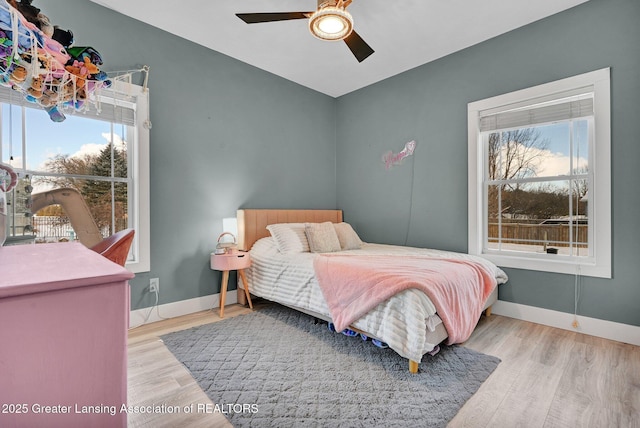 bedroom featuring ceiling fan, light hardwood / wood-style floors, and multiple windows