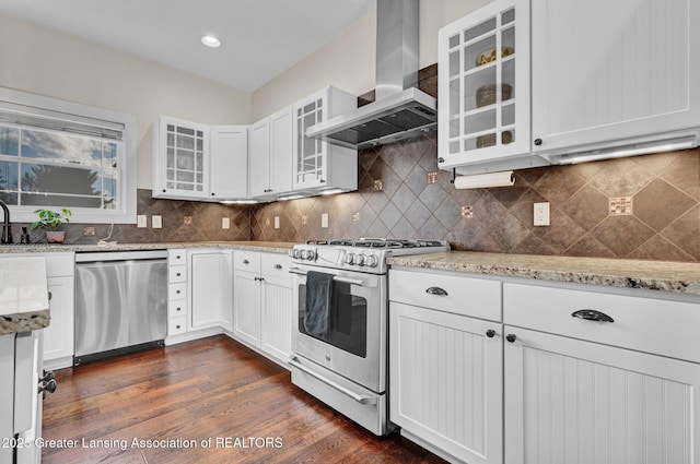 kitchen featuring white cabinetry, ventilation hood, light stone countertops, and appliances with stainless steel finishes