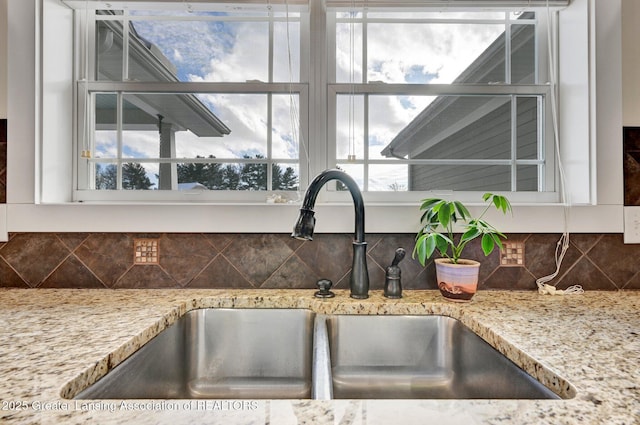 interior details featuring light stone countertops, sink, and decorative backsplash