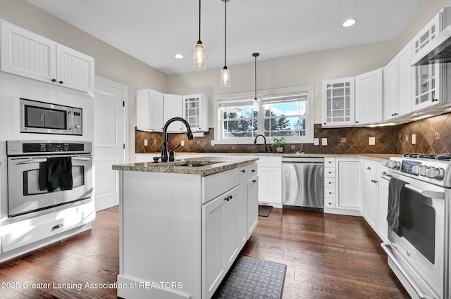 kitchen featuring a kitchen island with sink, light stone countertops, stainless steel appliances, and white cabinets