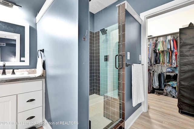 bathroom featuring an enclosed shower, vanity, and wood-type flooring