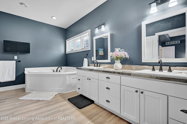 bathroom with vanity, wood-type flooring, and a tub