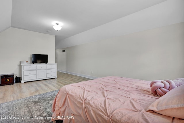 bedroom featuring lofted ceiling and light hardwood / wood-style flooring