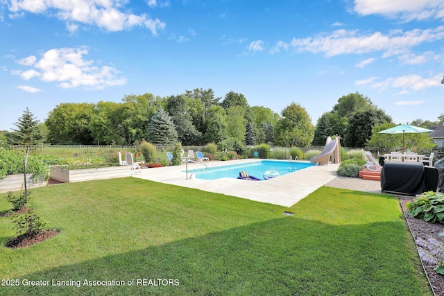 view of swimming pool with area for grilling, a water slide, a patio area, and a lawn