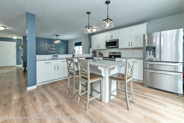 kitchen with decorative light fixtures, tasteful backsplash, white cabinetry, kitchen peninsula, and stainless steel appliances