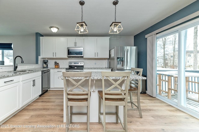 kitchen with stainless steel appliances, sink, white cabinets, and light stone counters