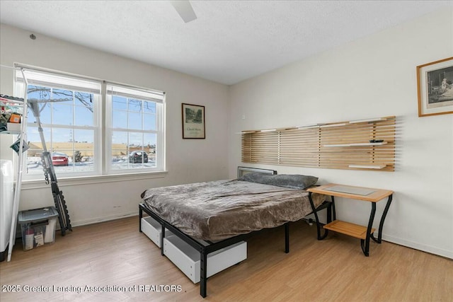 bedroom featuring ceiling fan, a textured ceiling, and light hardwood / wood-style floors