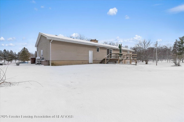 snow covered rear of property featuring a deck