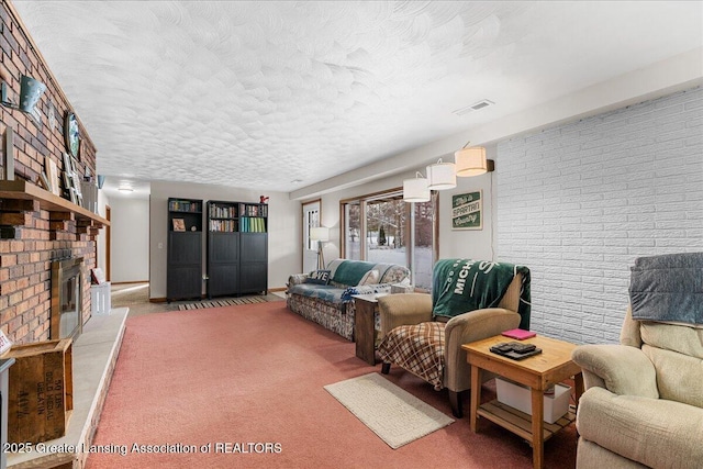 carpeted living room featuring a fireplace, a textured ceiling, and brick wall