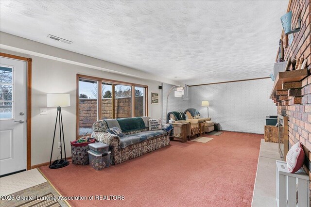 living room with brick wall, carpet, a textured ceiling, and a brick fireplace