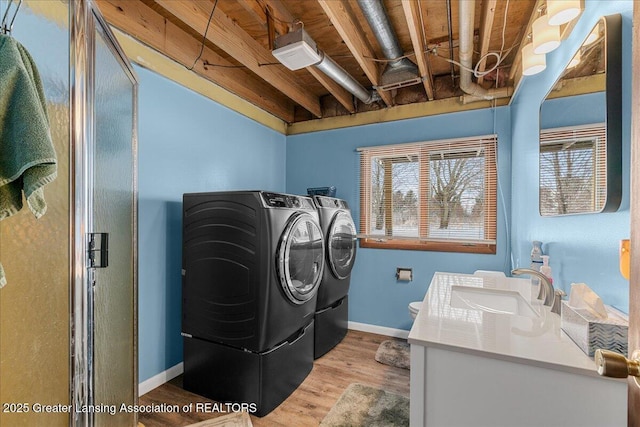 washroom with light wood-type flooring, sink, and washer and clothes dryer