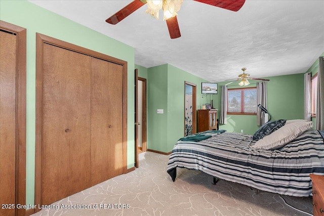 carpeted bedroom featuring a textured ceiling, ceiling fan, and two closets