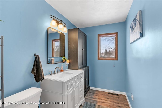 bathroom featuring vanity, wood-type flooring, and toilet