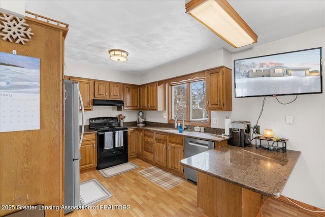 kitchen featuring appliances with stainless steel finishes, sink, light wood-type flooring, and kitchen peninsula