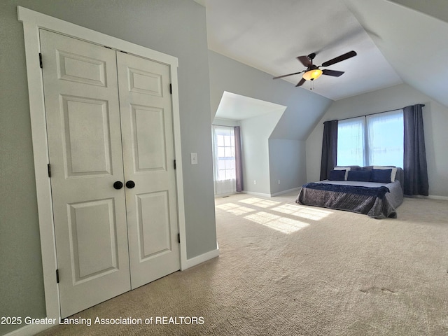 unfurnished bedroom featuring light carpet, vaulted ceiling, a closet, and ceiling fan