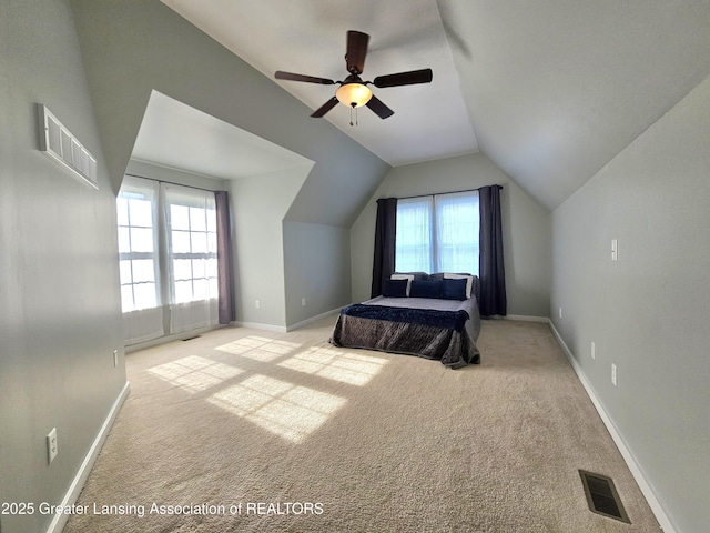 carpeted bedroom featuring multiple windows, vaulted ceiling, and ceiling fan